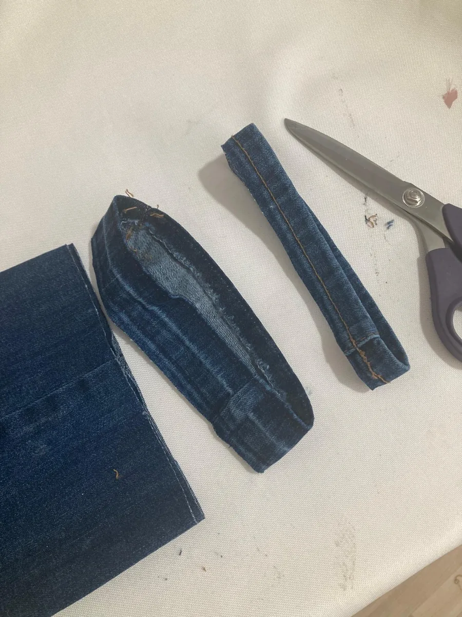 Abgetrennter Originalsaum einer Jeans neben der Schere