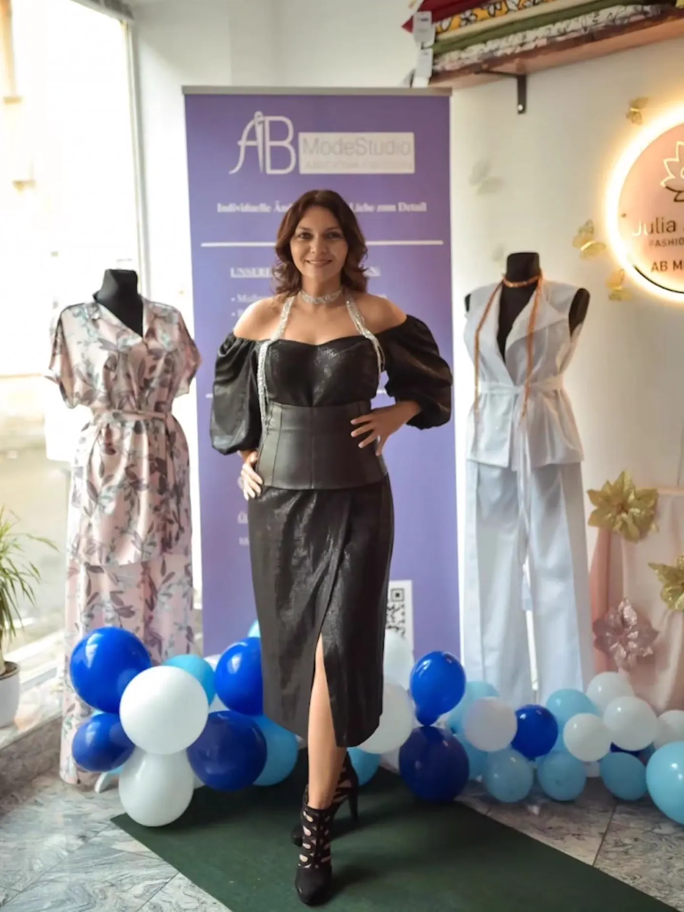 Model in schwarzem Korsagenoberteil und langem Rock vor dem Roll-up von AB ModeStudio